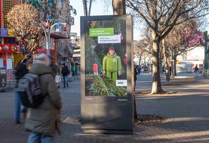 Eine Person steht vor einem Outdoor Bildschirm mit Werbung im Wiener Prater