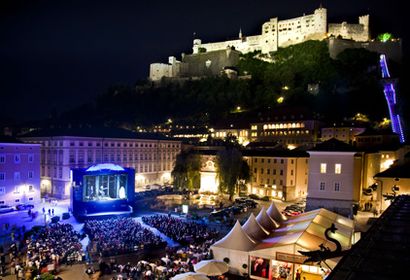 Festspielnächte Salzburg. Im Vordergrund eine große Videowall mit Publikum und im Hintergrund die Burg von Salzburg