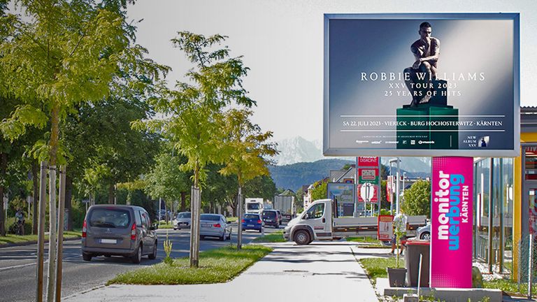 Plakat Robie Williams auf LED Wall neben einer befahren Straße